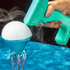 Pistolet à bulles turquoise déposant une bulle de fumée blanche sur un verre cornet à cocktail