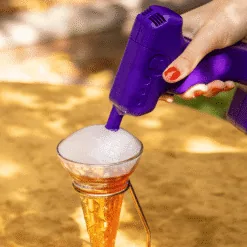 Pistolet à fumée violet déposant un nuage aromatique sur un cocktail en cornet doré en extérieur