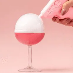 Pistolet rose Flavour Blaster déposant une bulle de fumée blanche sur un verre cocktail rose