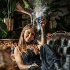 Mujer sonriente con un cóctel humeante con efecto de hielo seco en un salón acogedor