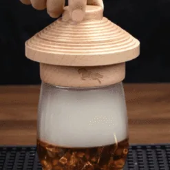 Couvercle fumoir western en bois posé sur verre de whisky rempli de fumée, copeaux en combustion