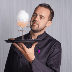 Barman présentant sur plateau noir le verre flamant rose coiffé d'une mousse de bulles aromatisées