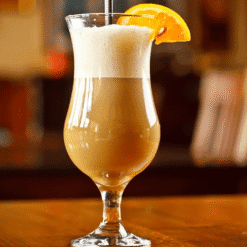 Cocktail crémeux café-lait dans un verre ouragan coiffé de mousse, garni d'une tranche d'orange