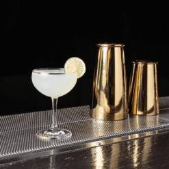 Shaker Boston doré et coupe à cocktail blanc garnie d'une rondelle de citron