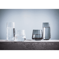 Quatre gobelets Ava en verre teinté transparent et gris fumé alignés sur muret de pierre, deux finitions
