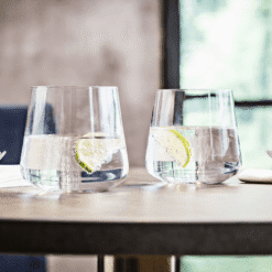 Deux gobelets Ava en verre transparent remplis d'eau garnie de citron sur table en bois en ambiance