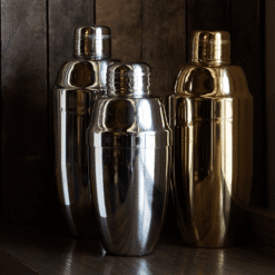 Trois shakers cobbler Madison argent et doré posés sur un meuble en bois ambiance tamisée