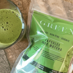 Sachet de capsules pure matcha Green a cote d'un verre de the matcha mousseux sur table en bois