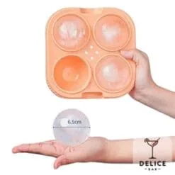 Moule silicone orange à quatre glaçons sphériques tenu en main, boule de glace de 6,5 cm Délice Bar