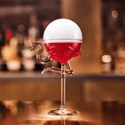 Verre flamant rose garni d'un cocktail rouge surmonté d'une bulle de fumée aromatisée au bar