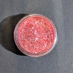 Pot ouvert de paillettes comestibles rose corail scintillantes pour décorer cocktails vue de dessus
