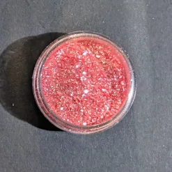 Pot ouvert de paillettes comestibles rose corail scintillantes pour décorer cocktails vue de dessus