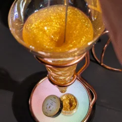 Mousse cocktail dorée pailletée tourbillonnant dans un verre sur support cuivré avec mousseur