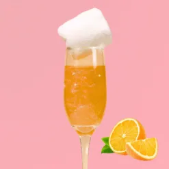 Flûte de cocktail orange pétillant garnie de barbe à papa blanche et tranches d'orange douce