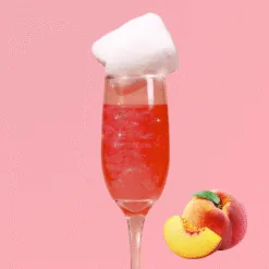 Flûte de cocktail rose pétillant garnie de barbe à papa blanche et tranches de pêche