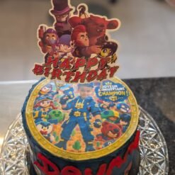 Gâteau sombre avec un disque comestible de jeu vidéo et la photo d’un enfant