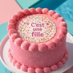 Gâteau rose avec un disque comestible à confettis et le message C’est une fille